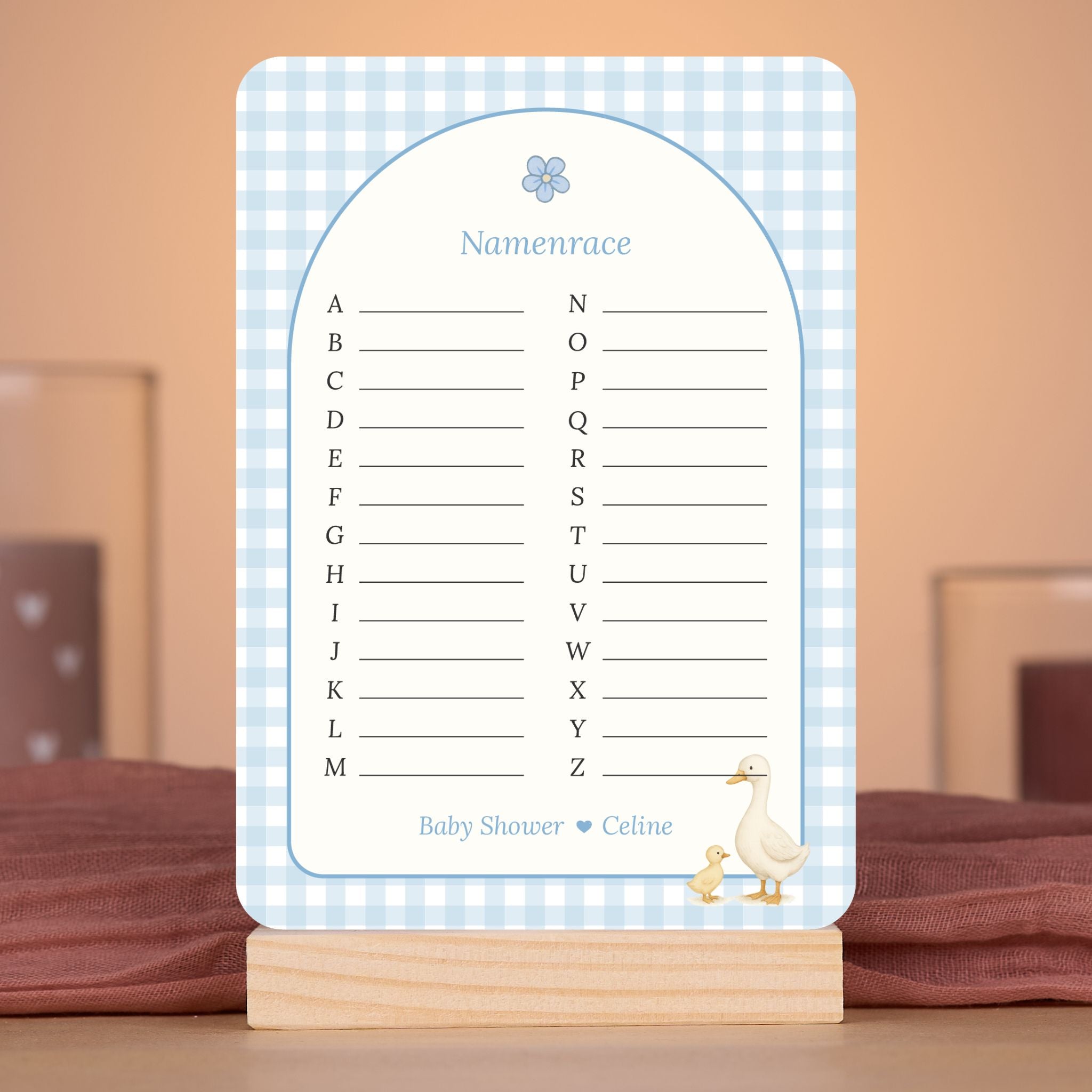 Namenrace kaart in gingham blauw met gansje in sfeervolle babyshower setting met decoratie, Studio Miron